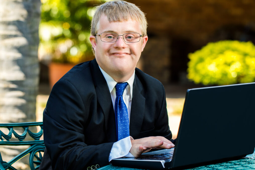 Young business man who has Down Syndrome working at a computer.