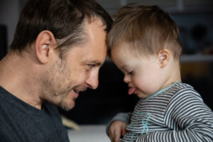 An adoring dad head to head with his child who is intent of what he is doing.